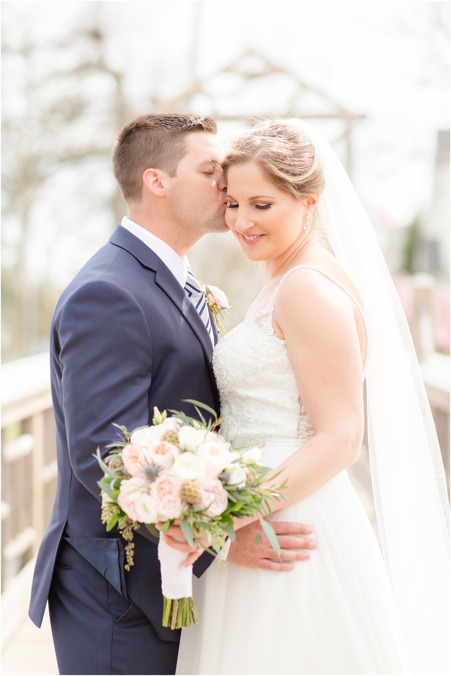 Bride and groom kissing on a bridge at Divine Park in Spring Lake 