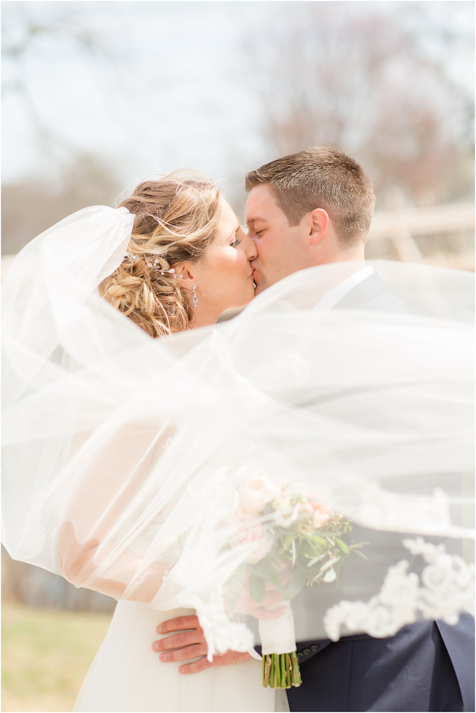 Romantic photo of bride and groom kissing in the wind