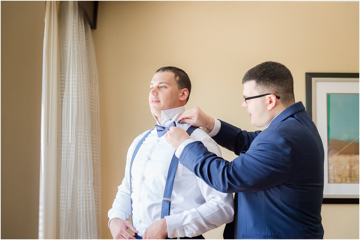 Best man helping groom with bow tie for wedding at Windows on the Water at Frogbridge in Millstone NJ