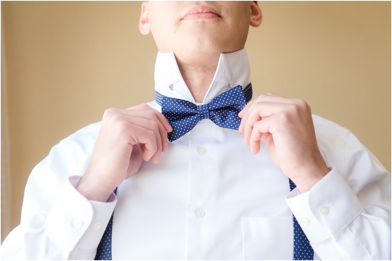 Groom straightening bow tie for wedding day