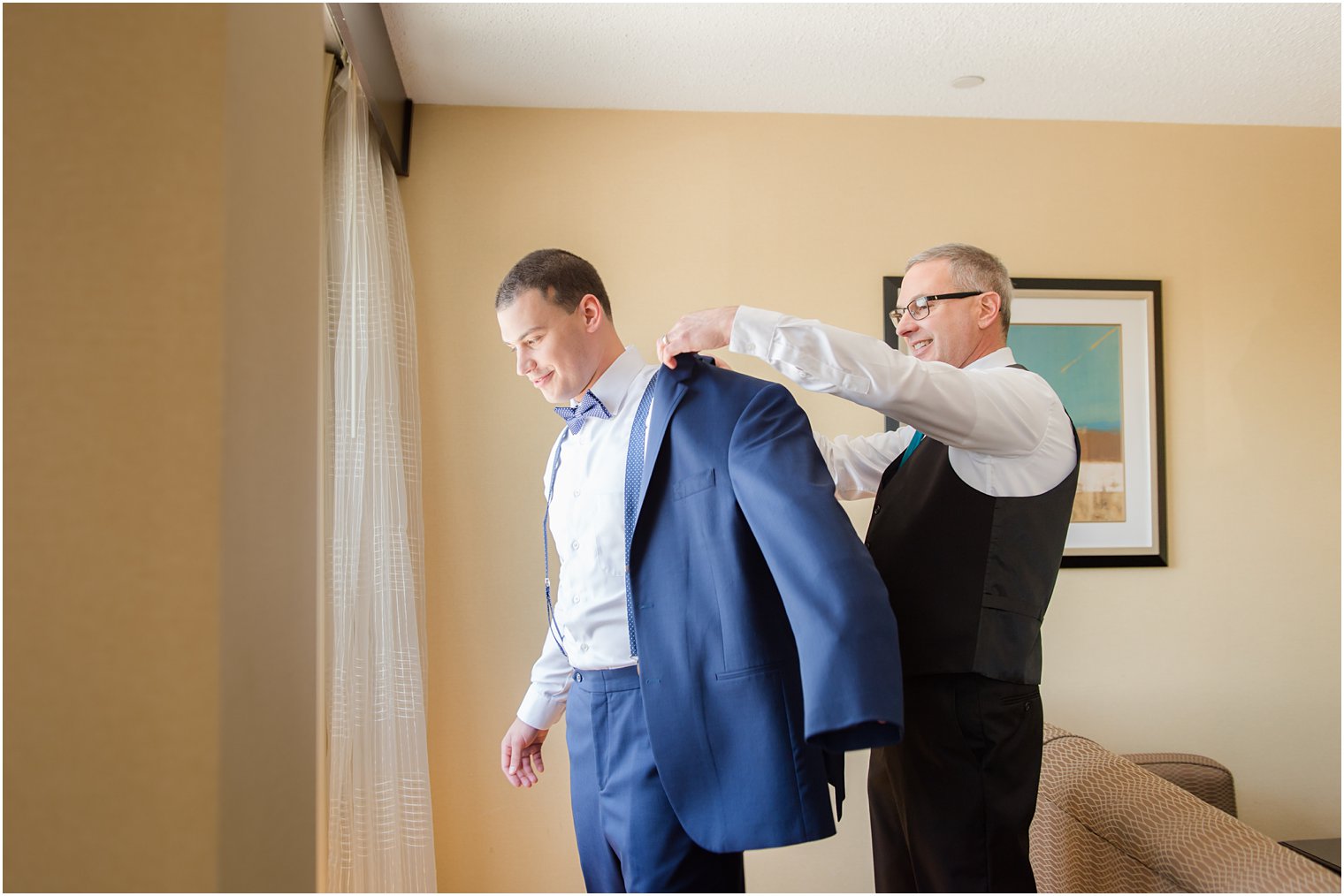 Groom's father helping him put on his jacket 