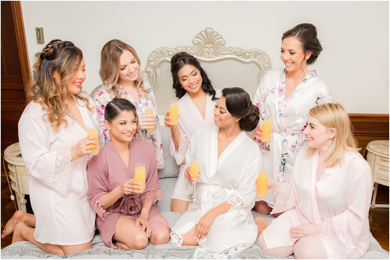 Bridesmaids drinking mimosas on bed