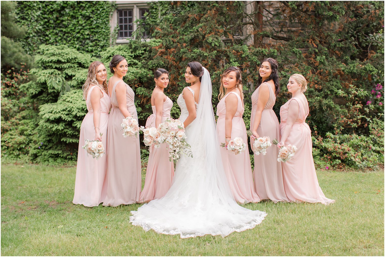 bridesmaids holding out bouquets from behind | The Castle at Skylands Manor Wedding Photos by Idalia Photography