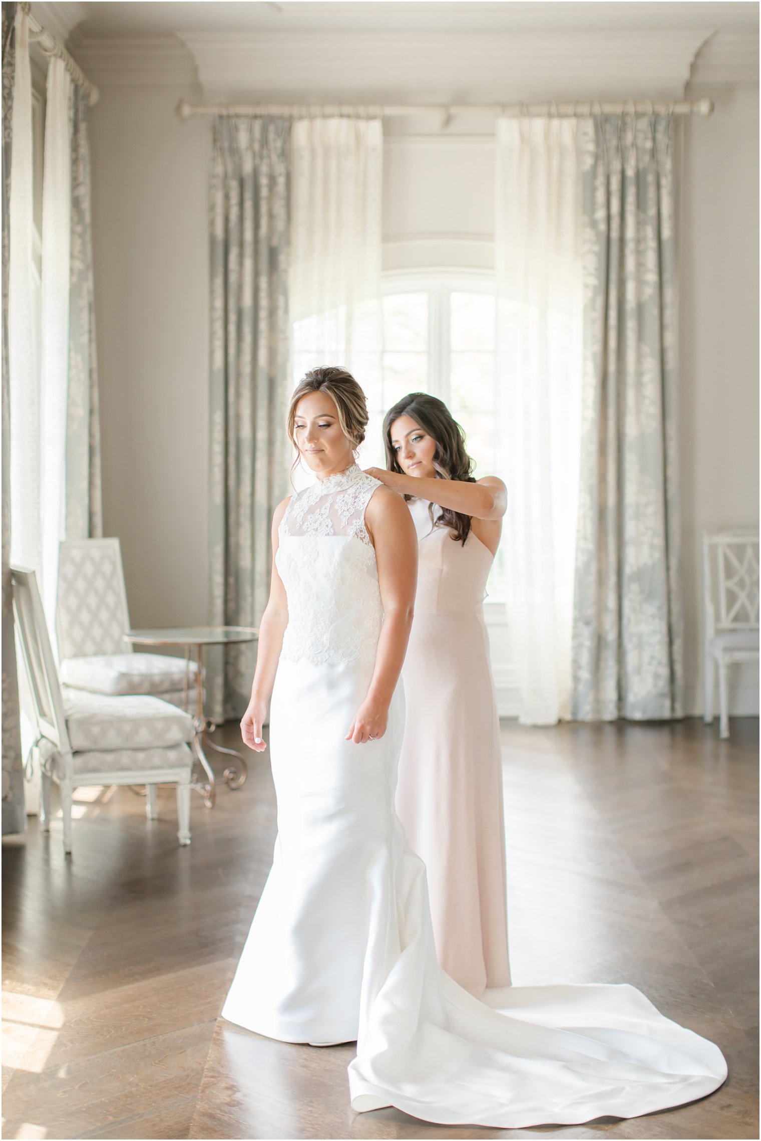 Maid of honor helping bride get dressed on wedding day at Park Chateau Estate and Gardens
