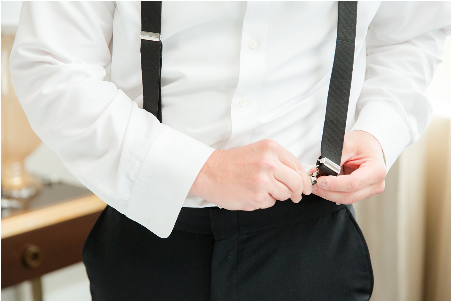 Groom putting on suspenders