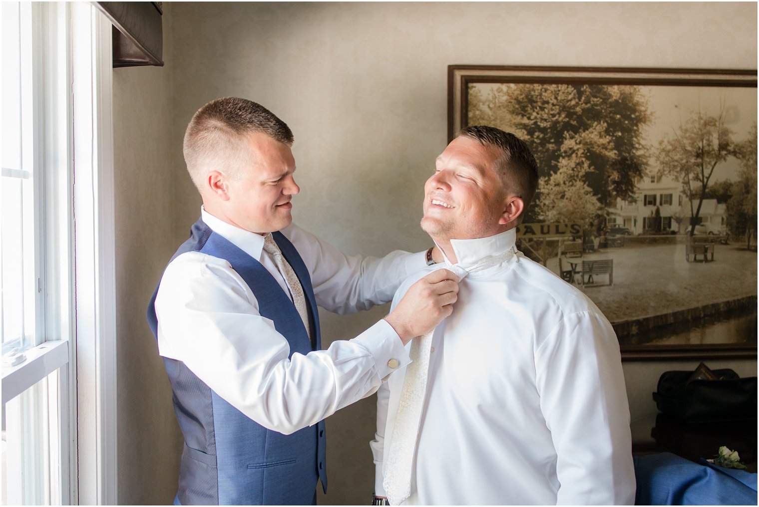 Groom having his tie put on by best man