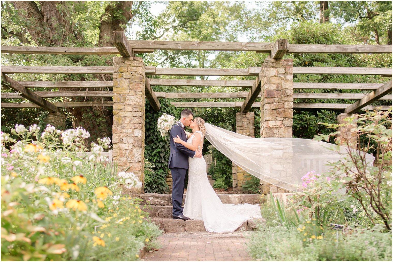 Bride and groom kissing and veil blowing in the wind 