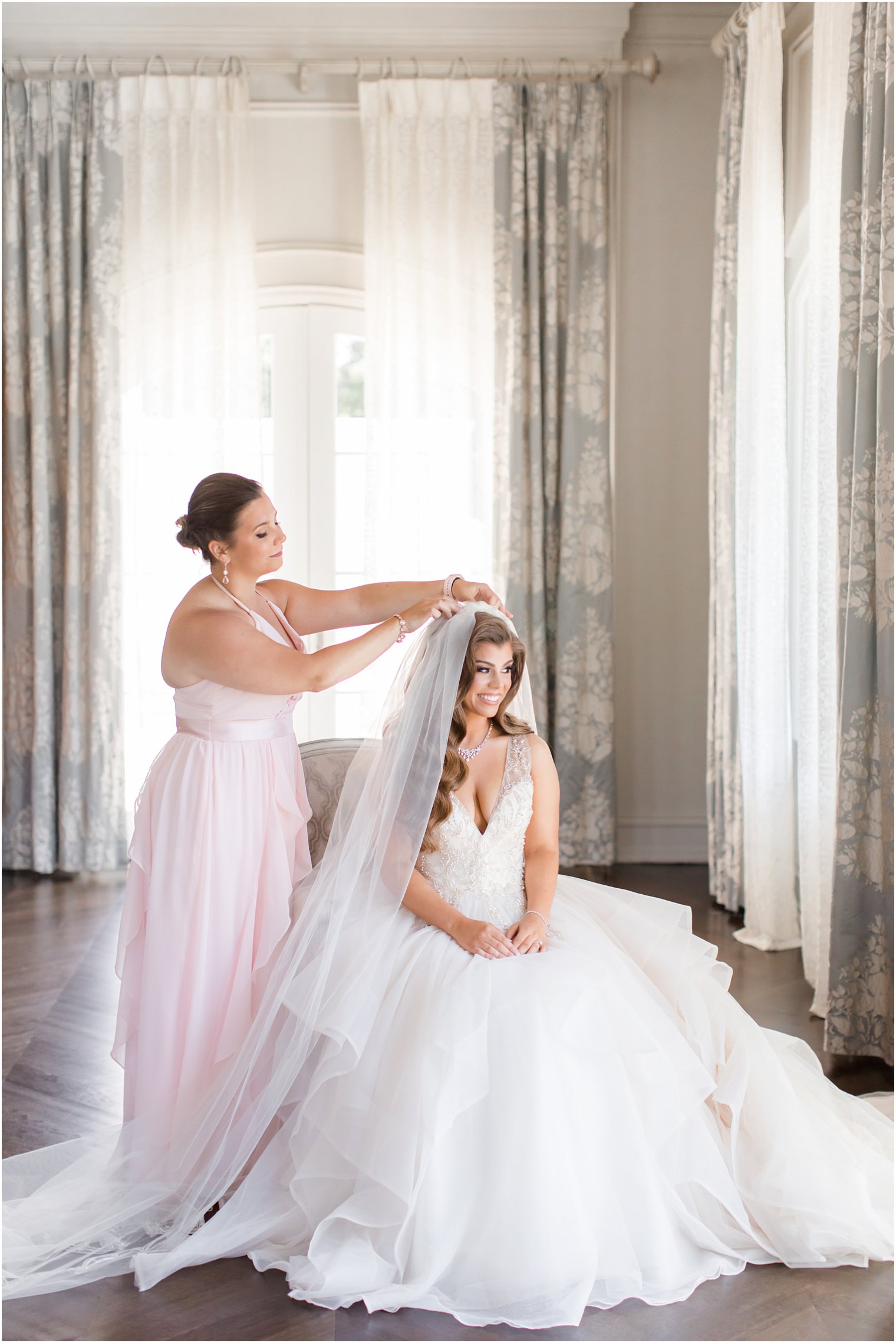 Maid of honor putting on bride's cathedral veil at Park Chateau Estate