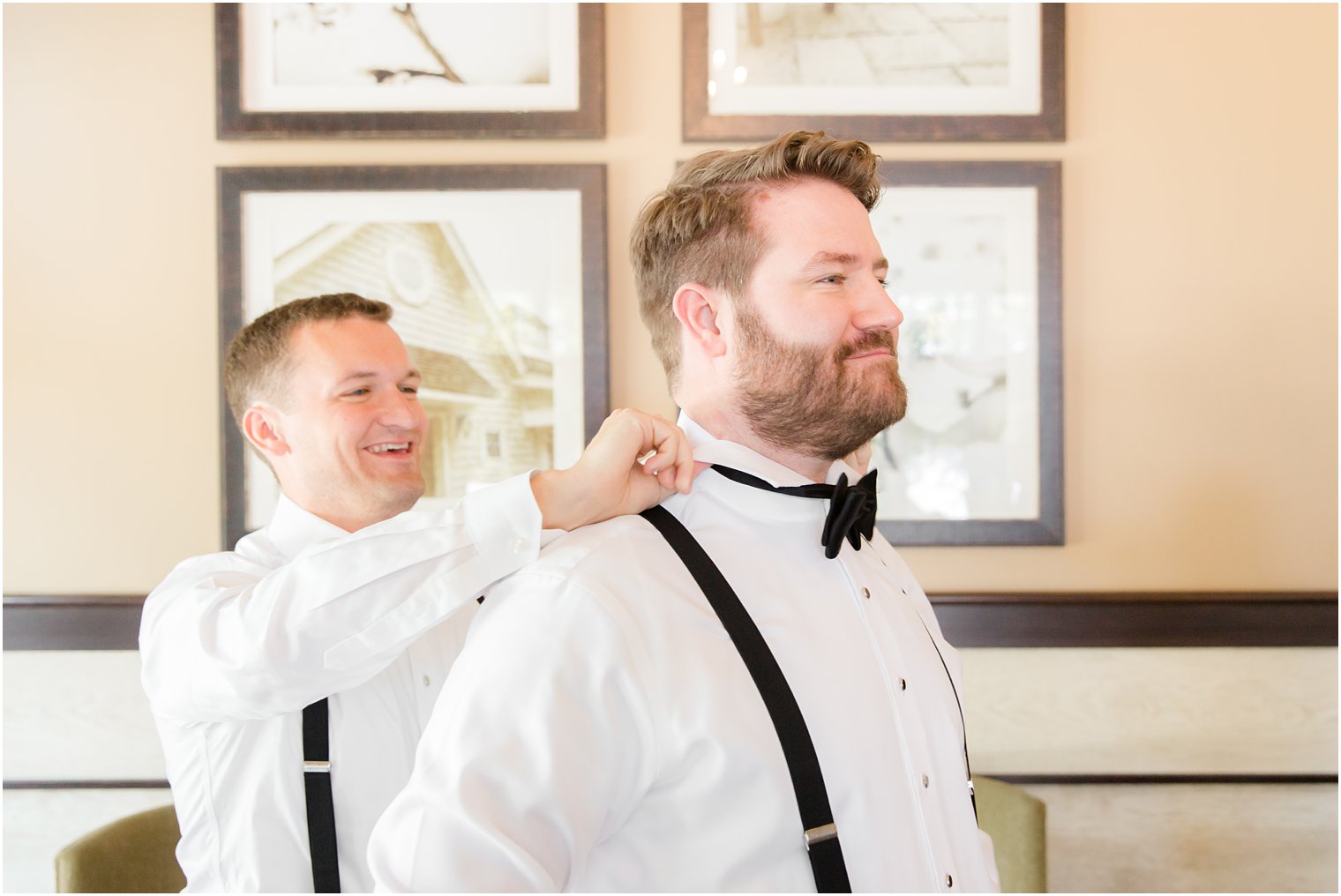 Best man helping groom put on his bow tie