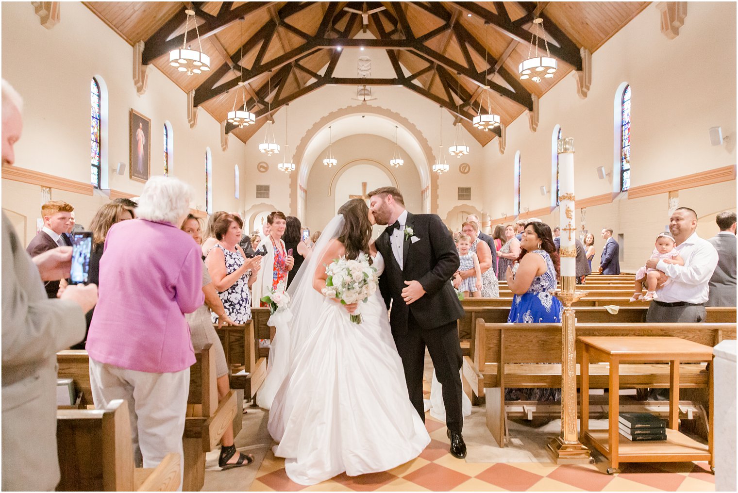 Bride and groom kissing during wedding recessional in St. Luke's Church in Ho-Ho-Kus