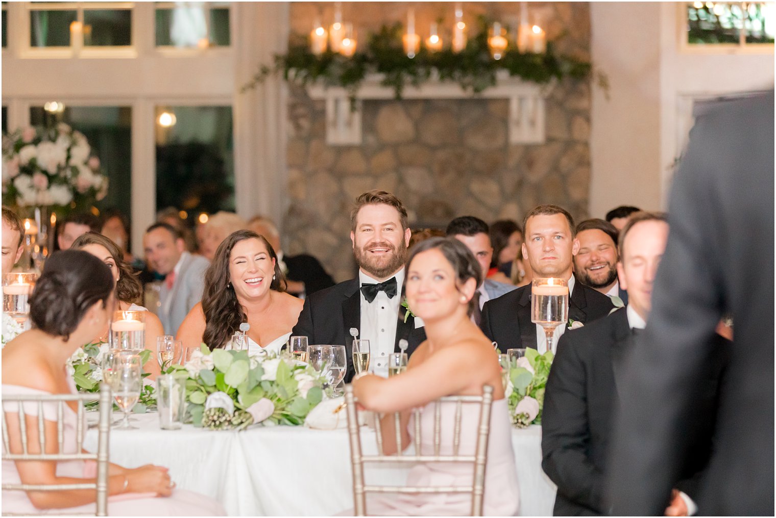 Bride and groom laughing at toasts during wedding reception 