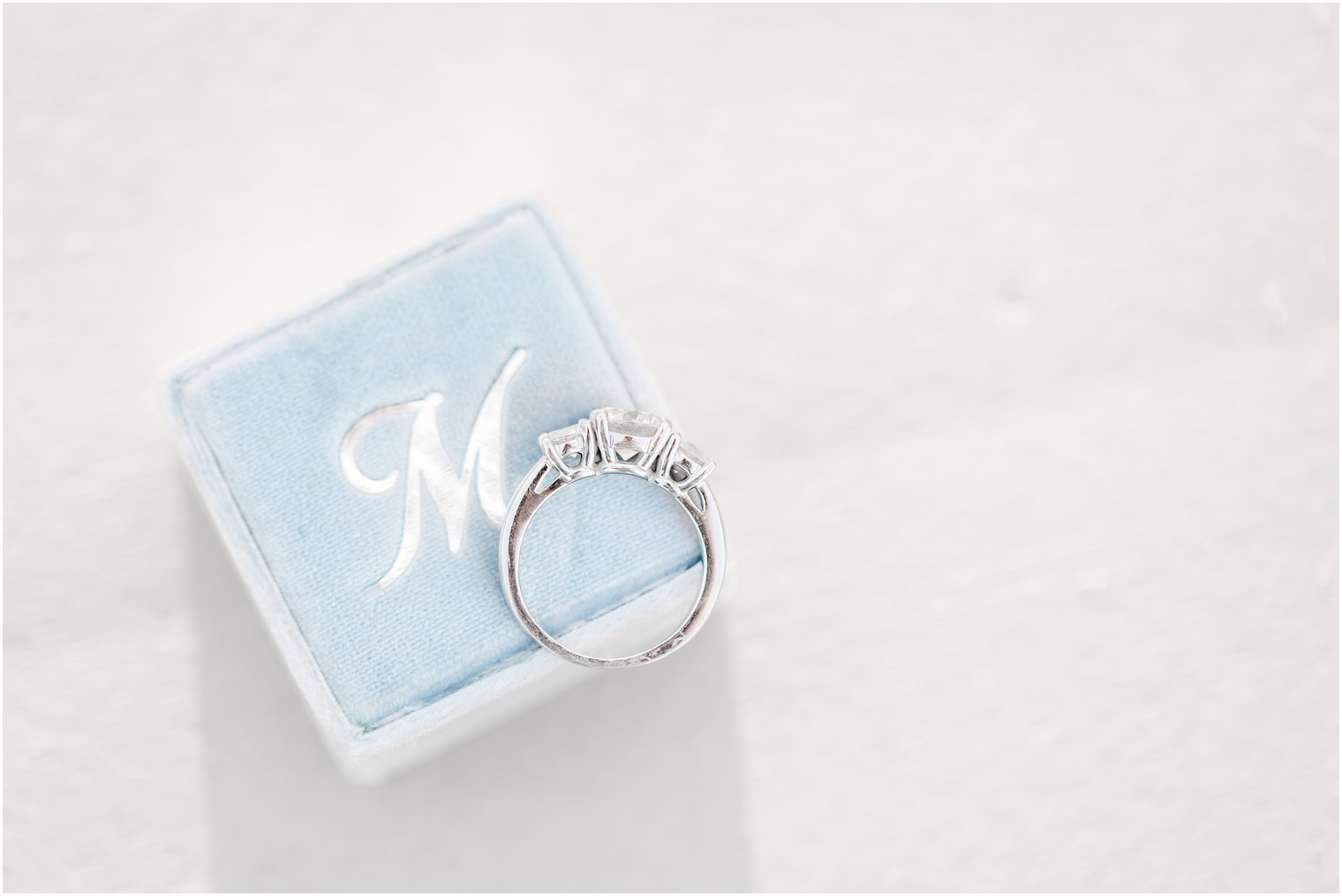 Engagement ring with three stones on a blue Mrs. Box
