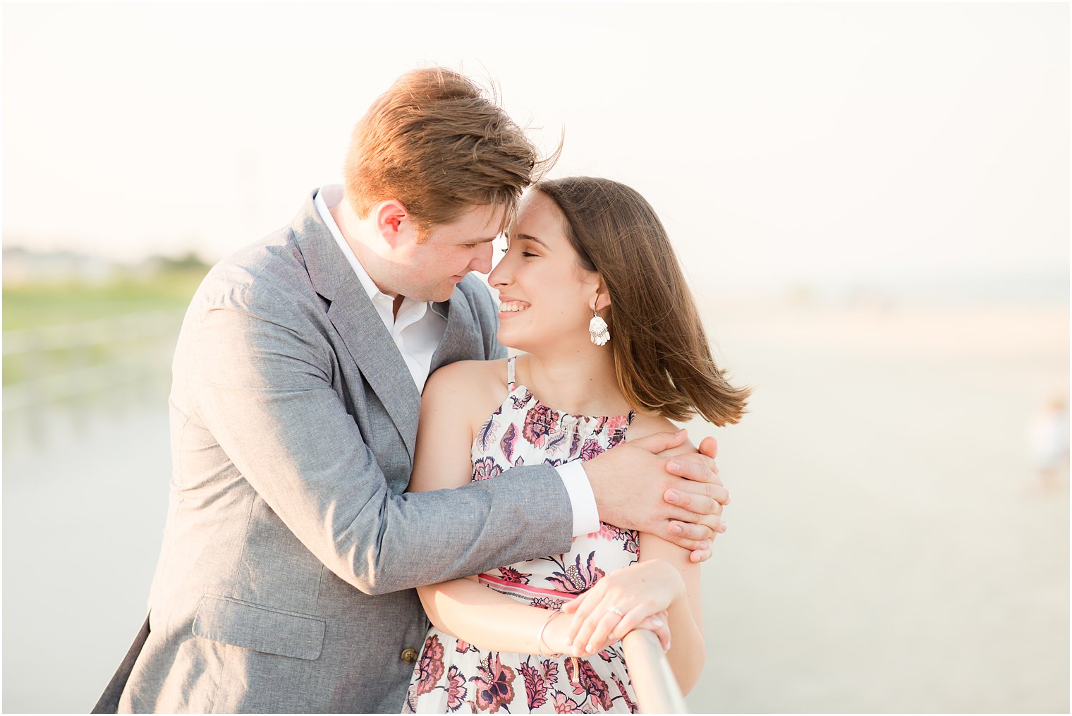 Romantic boardwalk engagement photos of groom hugging bride