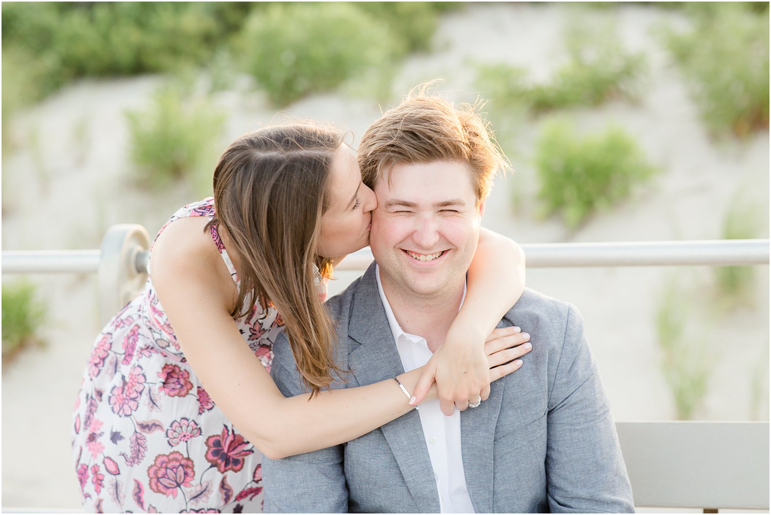 Bride kissing groom's cheek during engagement session at the boardwalk 