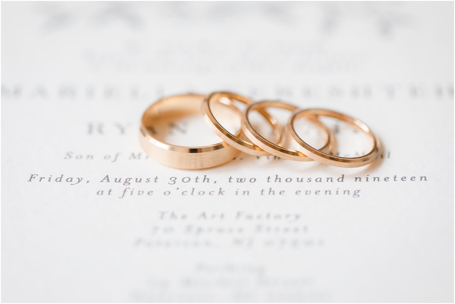 Gold wedding bands on invitation at Art Factory Studios in Paterson, NJ