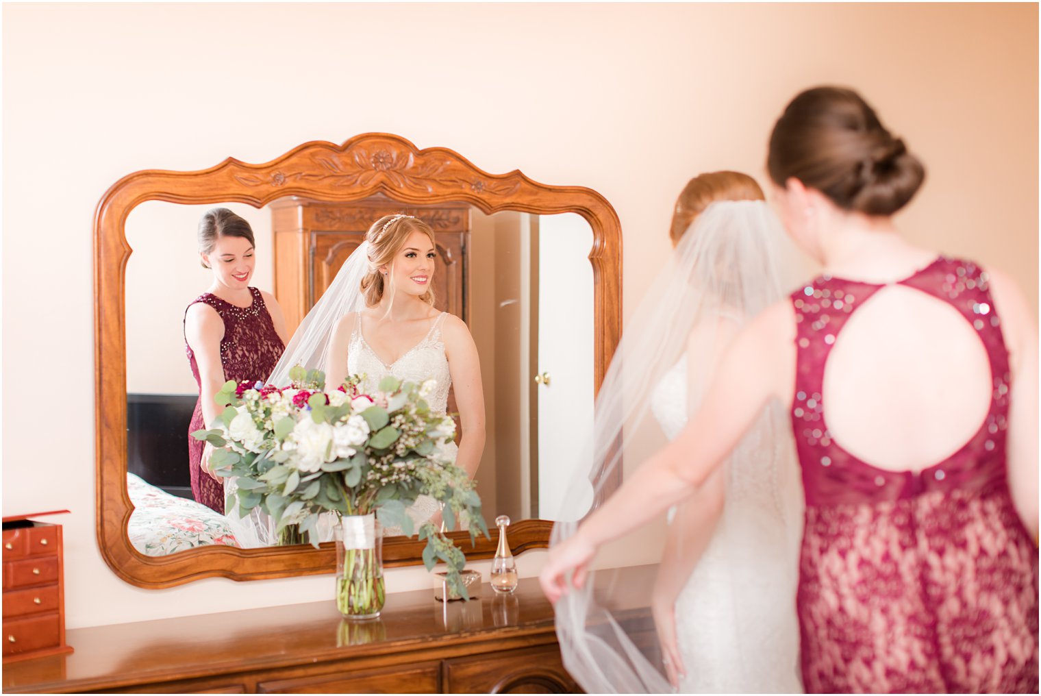 Bride getting ready with maid of honor in her parent's bedroom