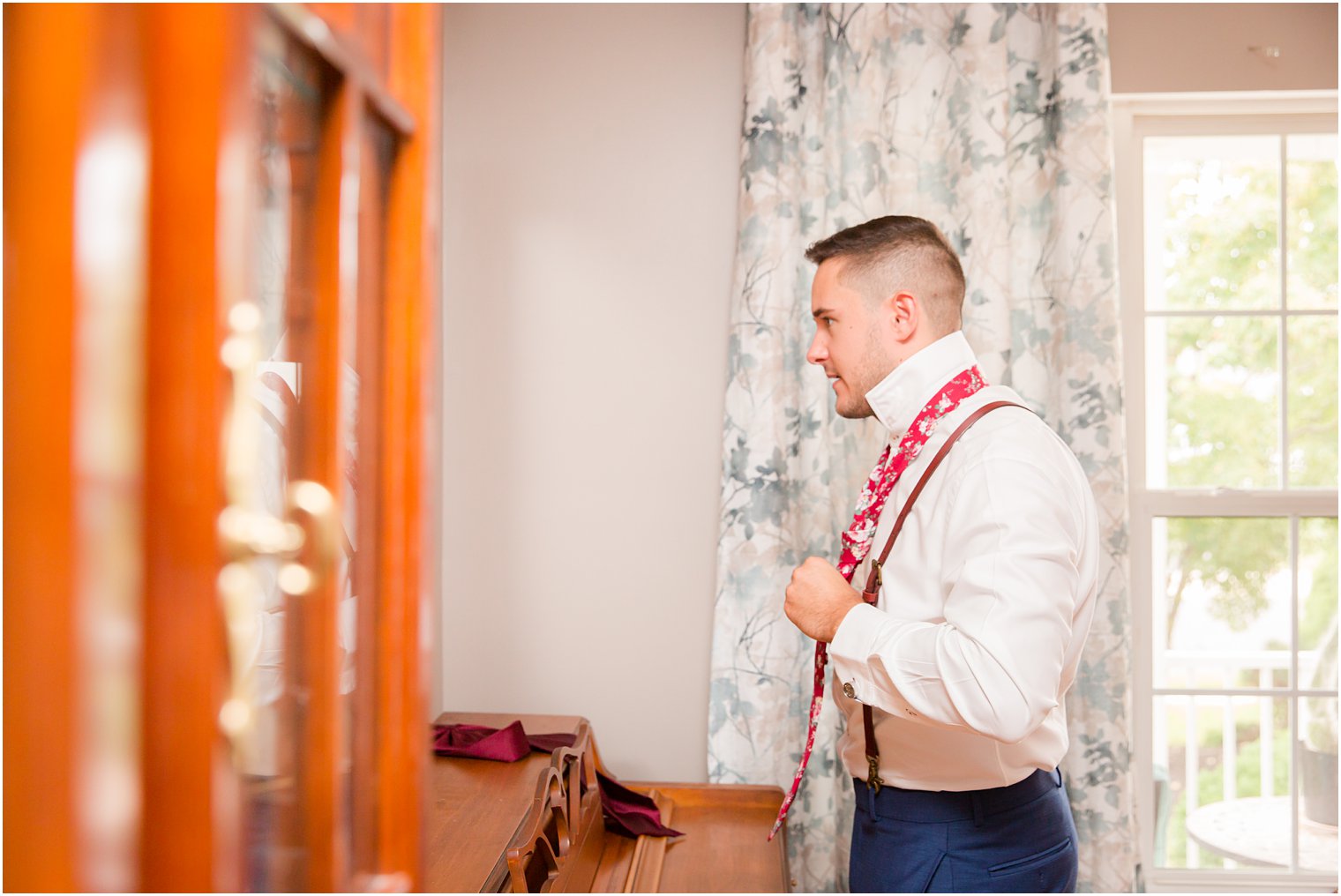Groom putting on his tie for his wedding day