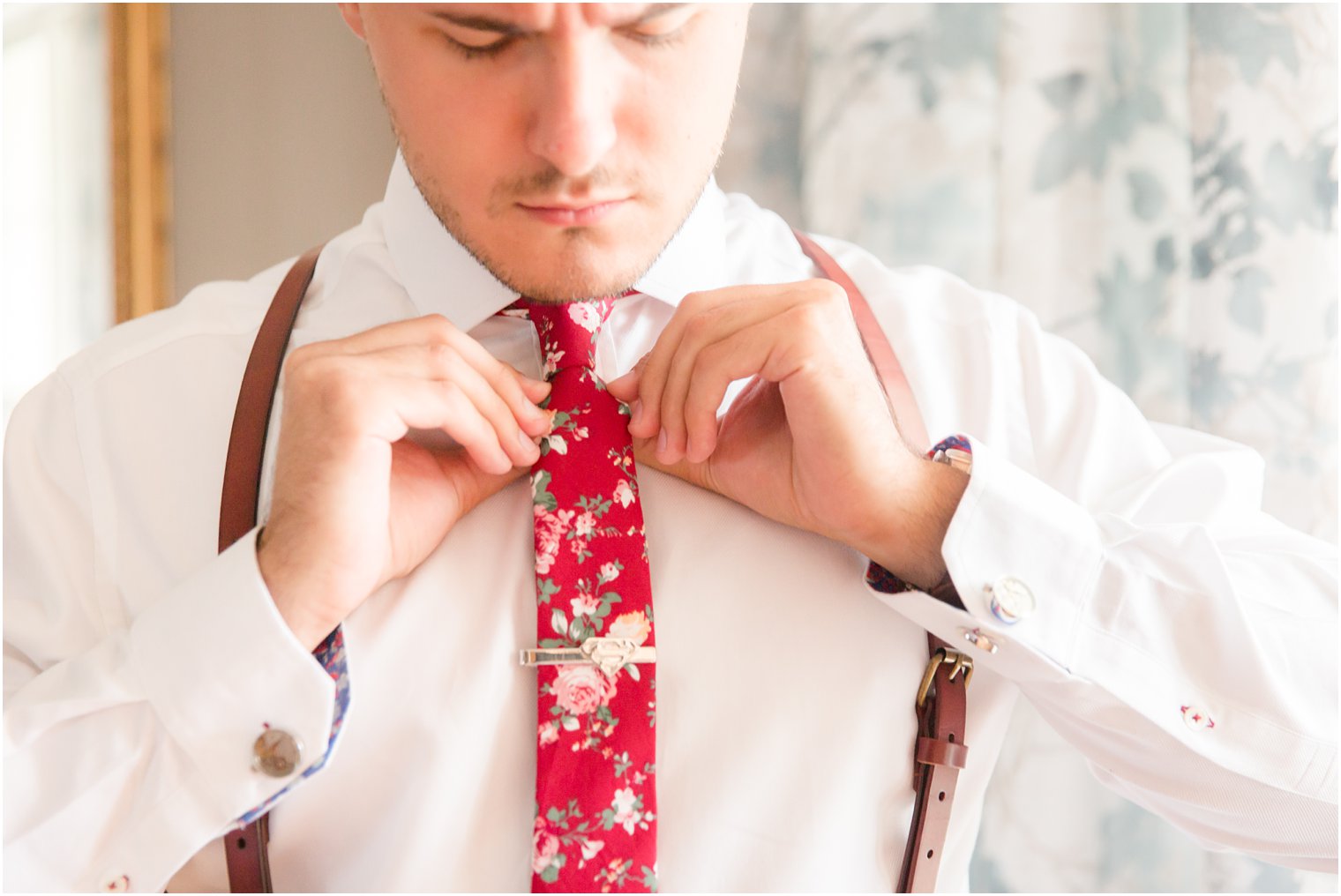 Groom tying his maroon tie
