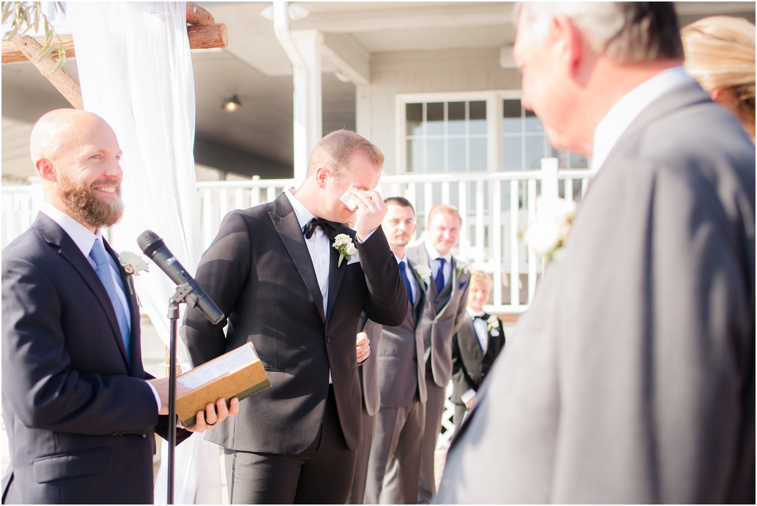 Groom crying during outdoor wedding ceremony at Brant Beach Yacht Club