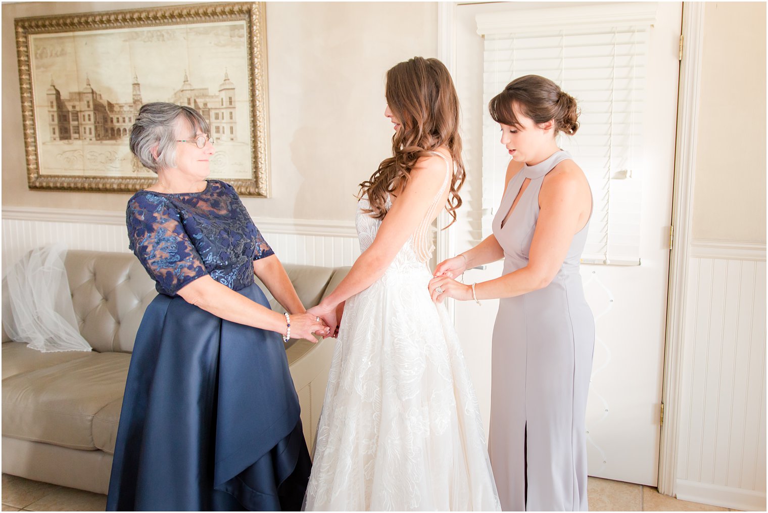 bride gets into wedding gown with mother and bridesmaid