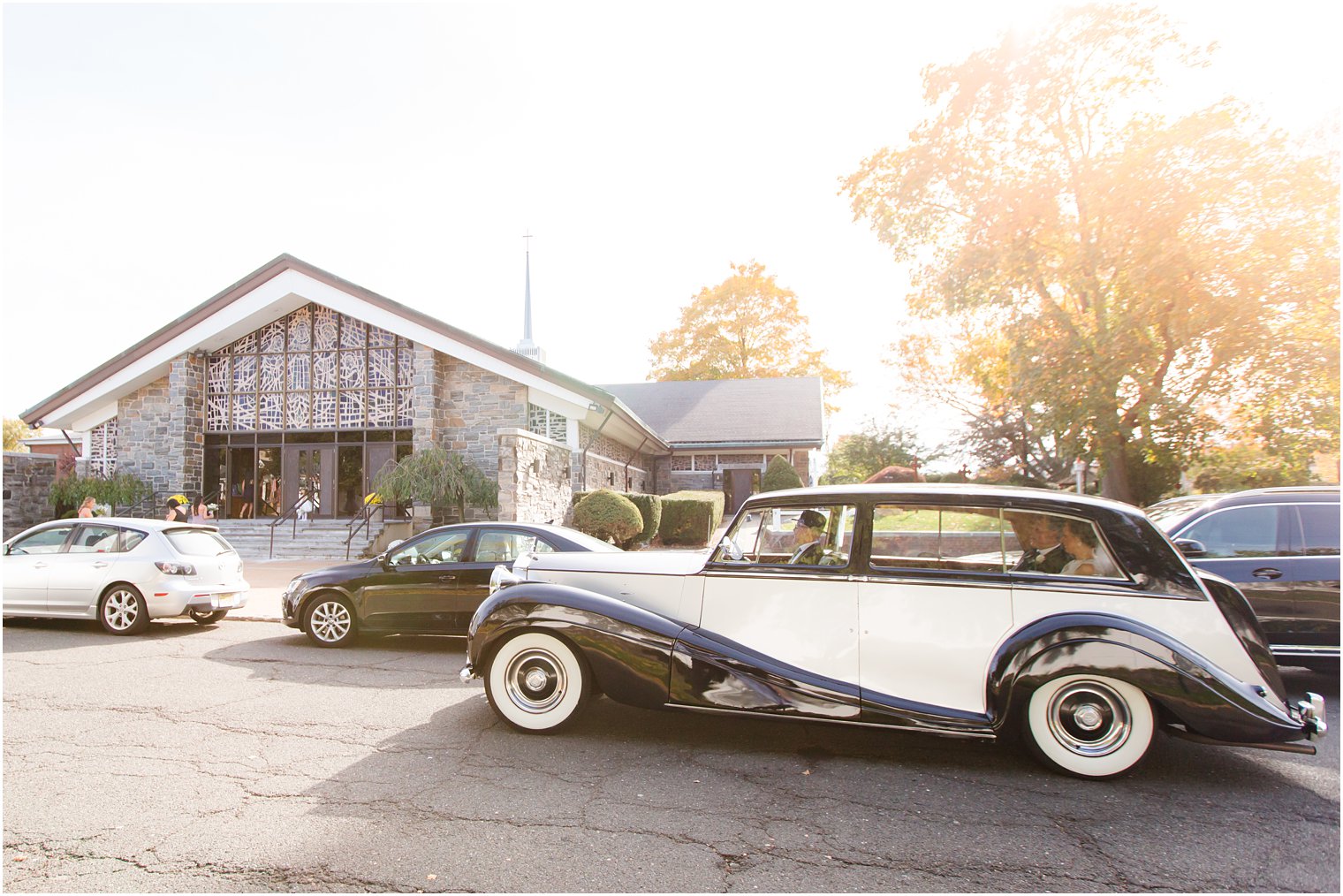 classic car pulls up bride to church for wedding ceremony