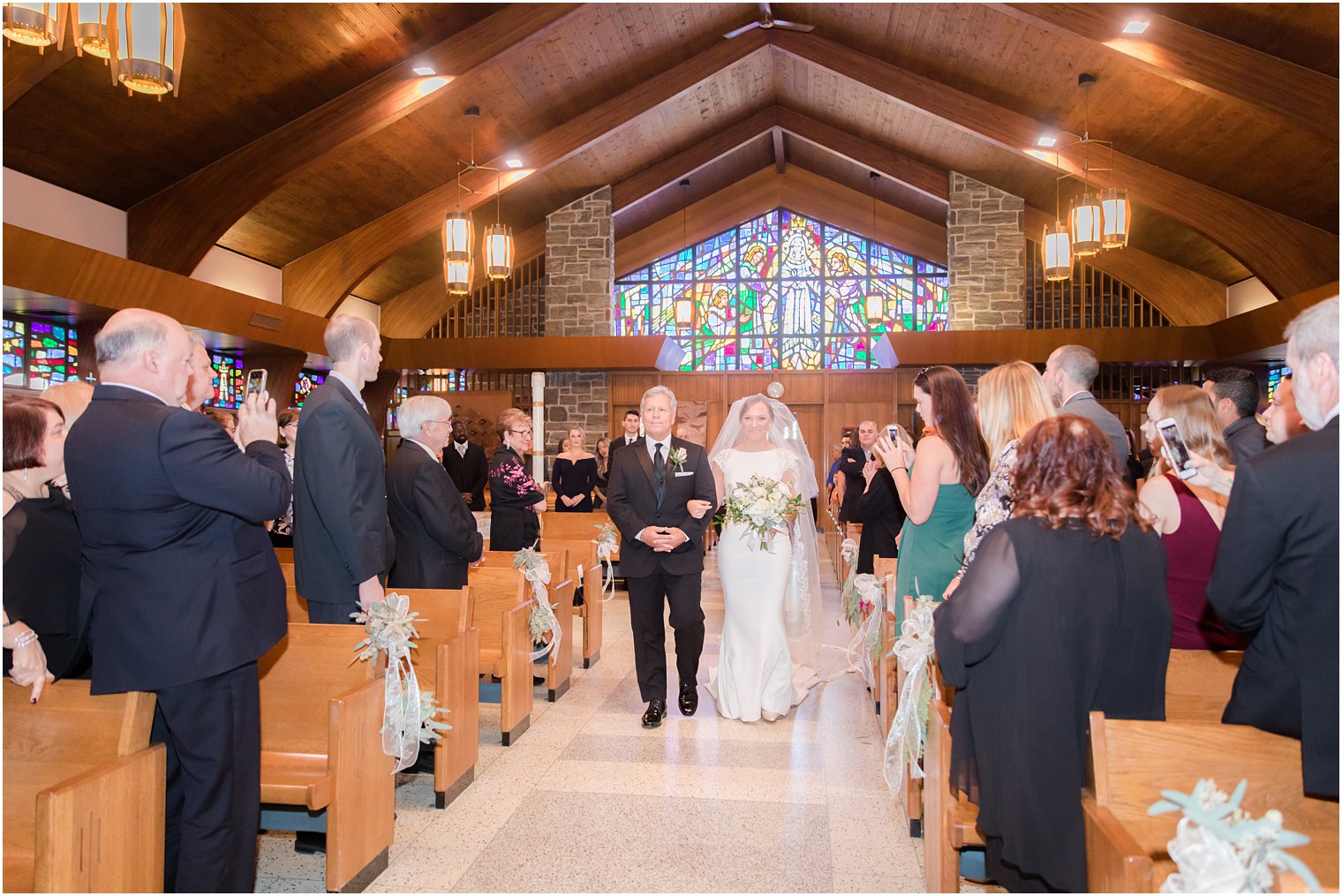 bride walks down the aisle with father photographed by Idalia Photography