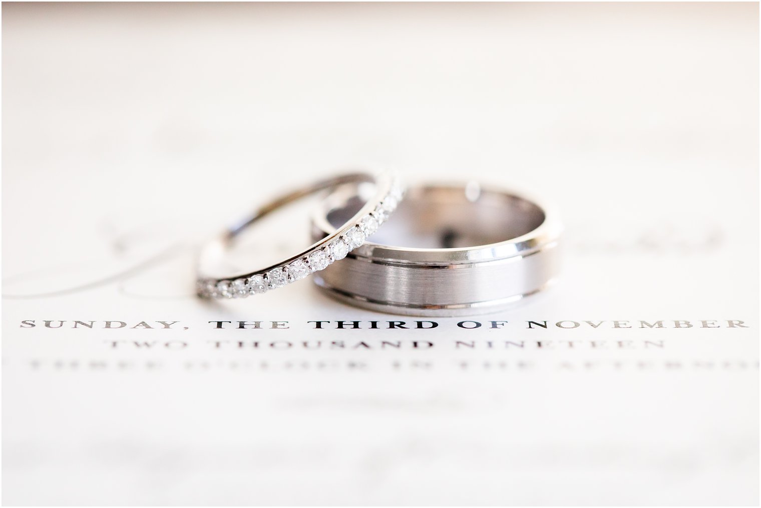 wedding bands sit on wedding invitation