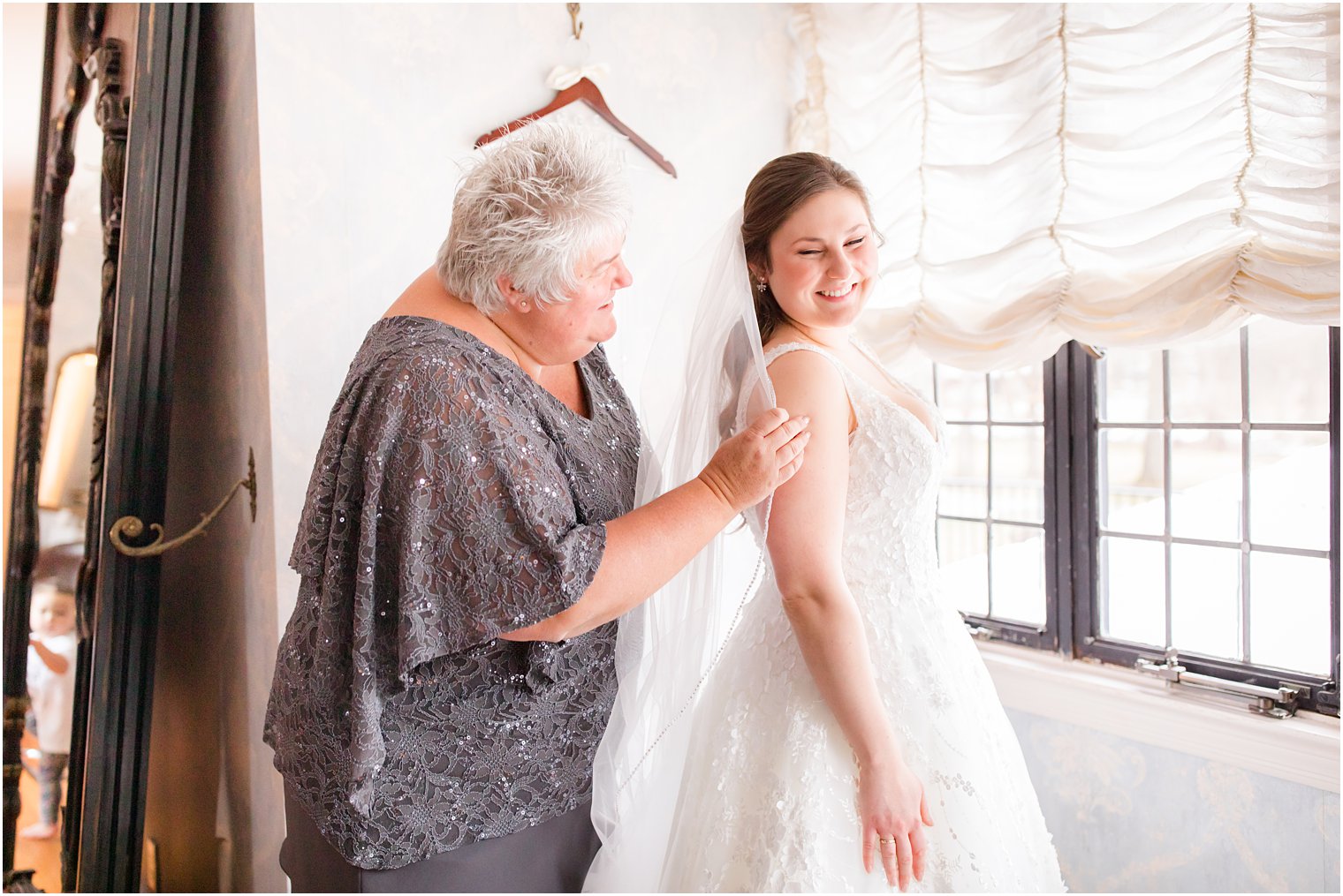 mother of the bride helping bride put on her veil