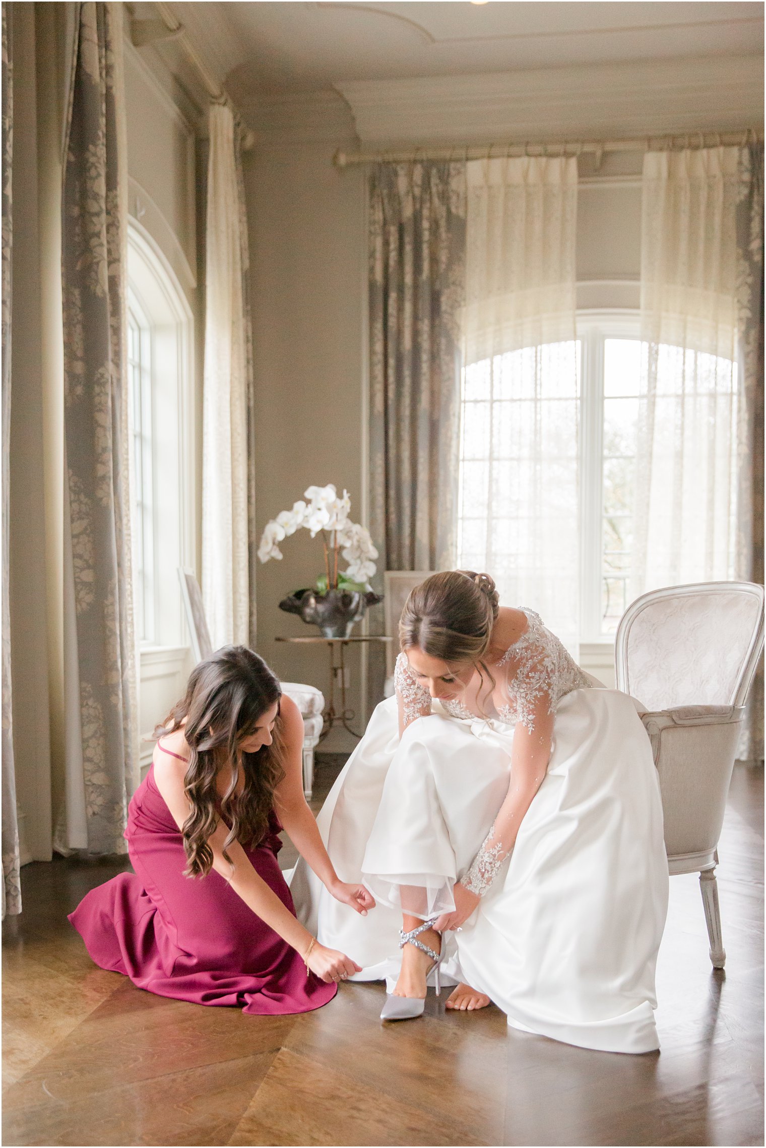 bride putting on her shoes with maid of honor