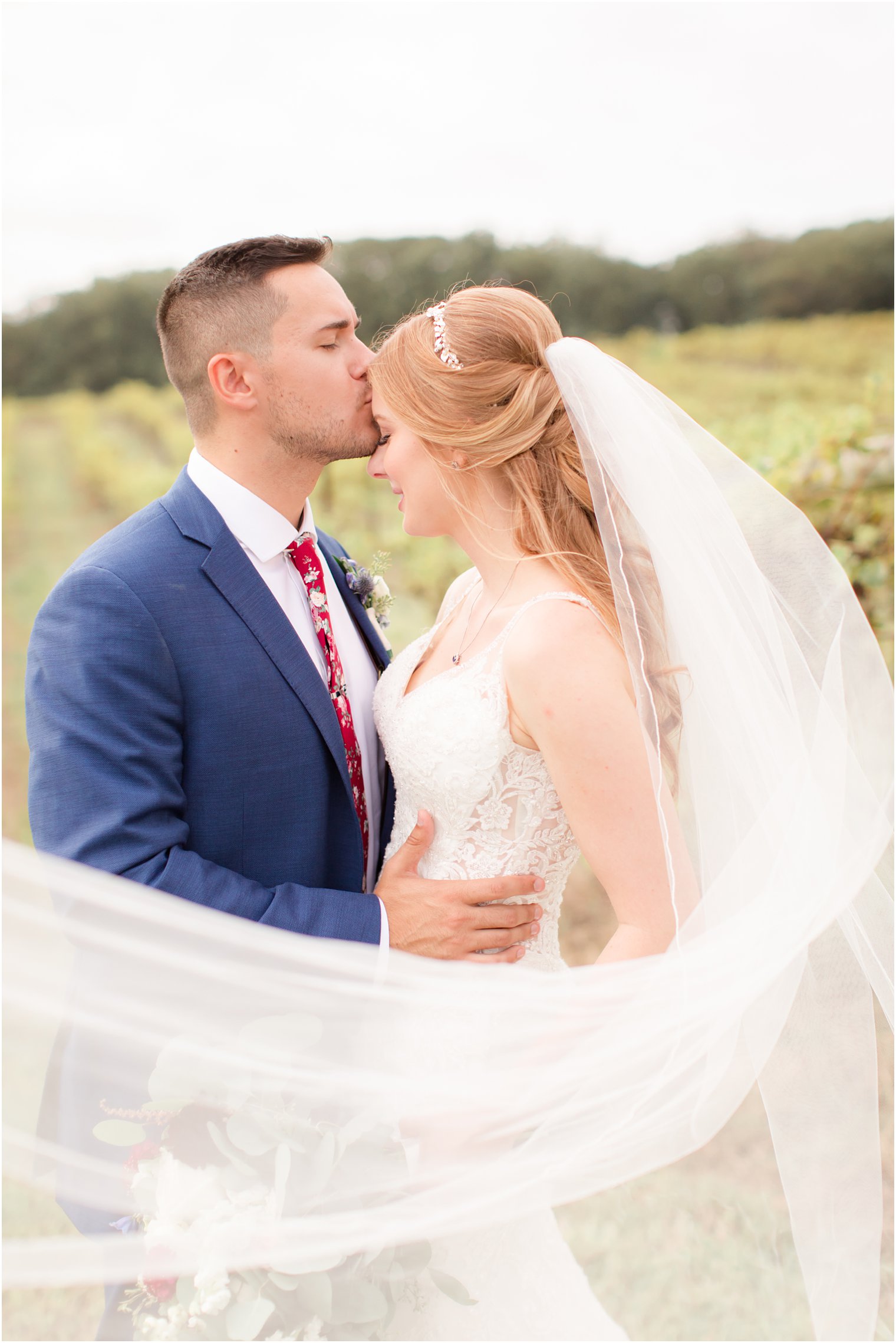 Groom kissing bride on forehead at Laurita Winery