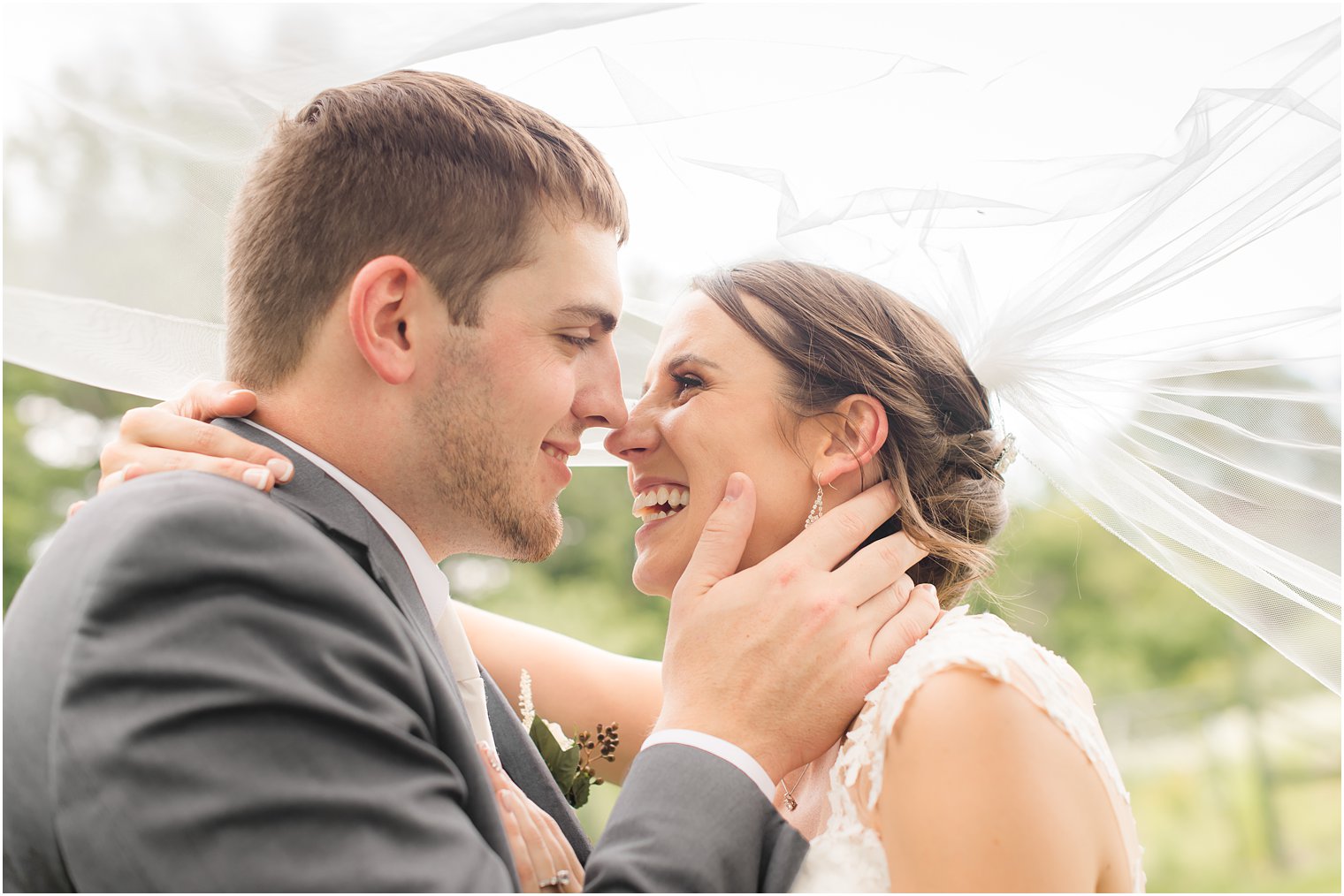 Bride and groom smiling under veil at Farmhouse at the Grand Colonial in Hampton, NJ