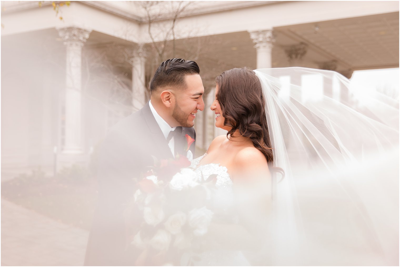 Bride and groom posing for photo with romantic veil at Palace at Somerset Park in Somerset, NJ