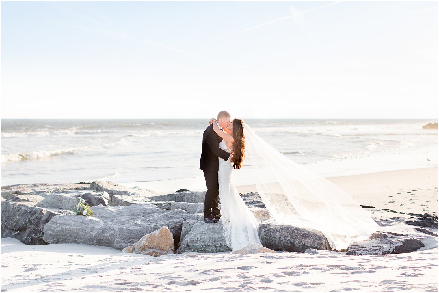 Bride and groom standing on jetty at the beach 