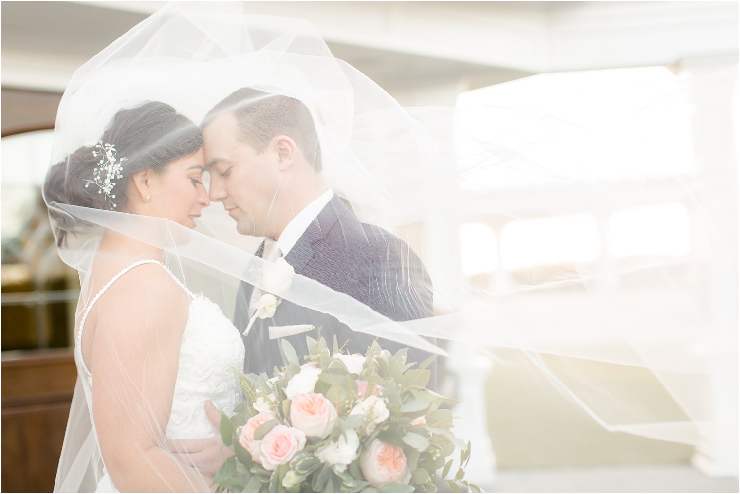 Bride and groom posing for wedding photo under the veil 