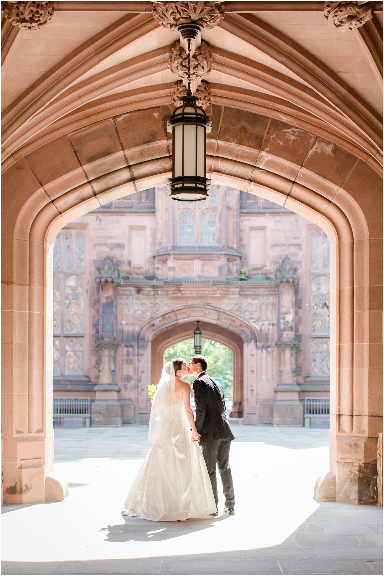 Bride and groom walking away under an arch at Princeton University