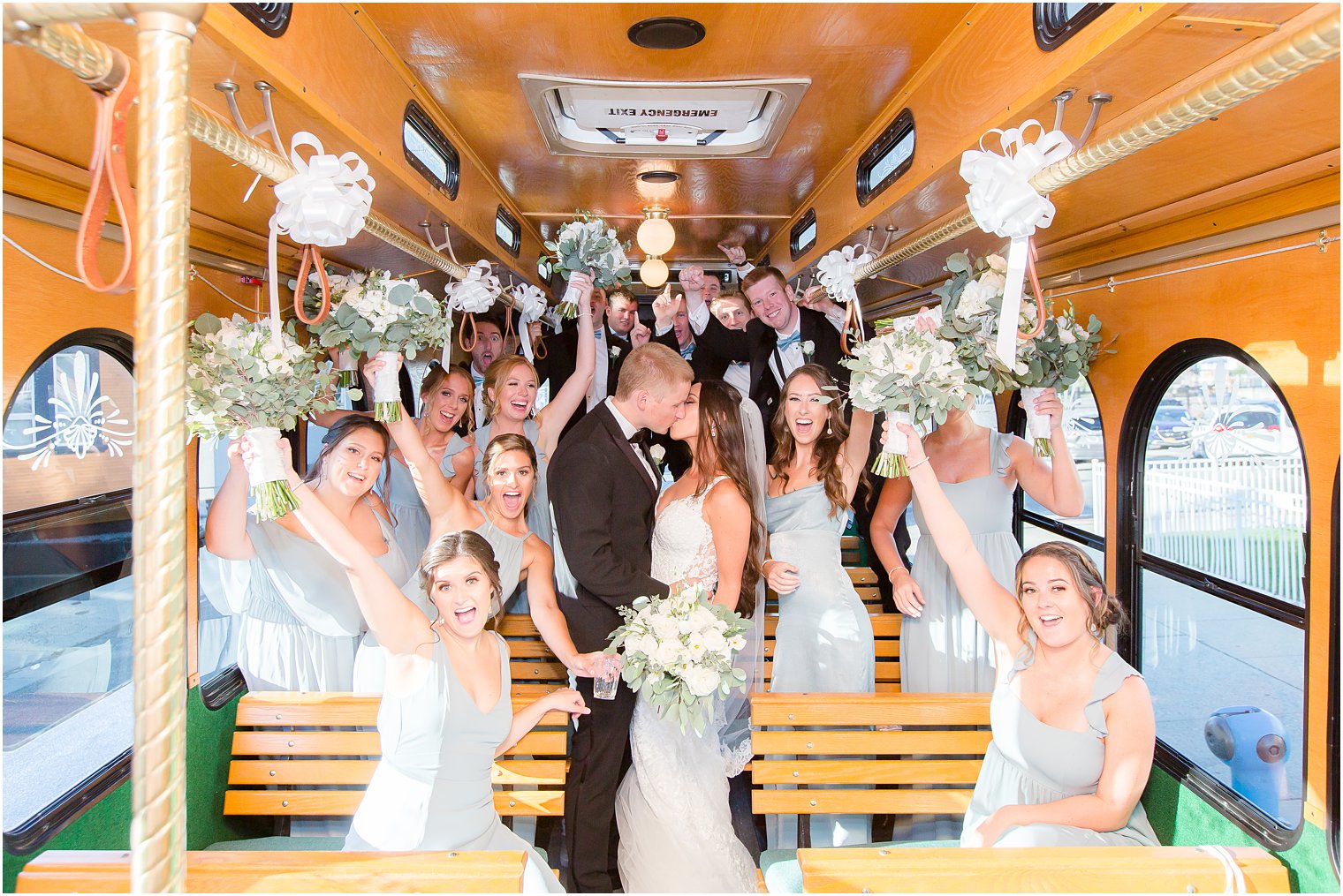 Bridal party cheering for bride and groom in trolley 