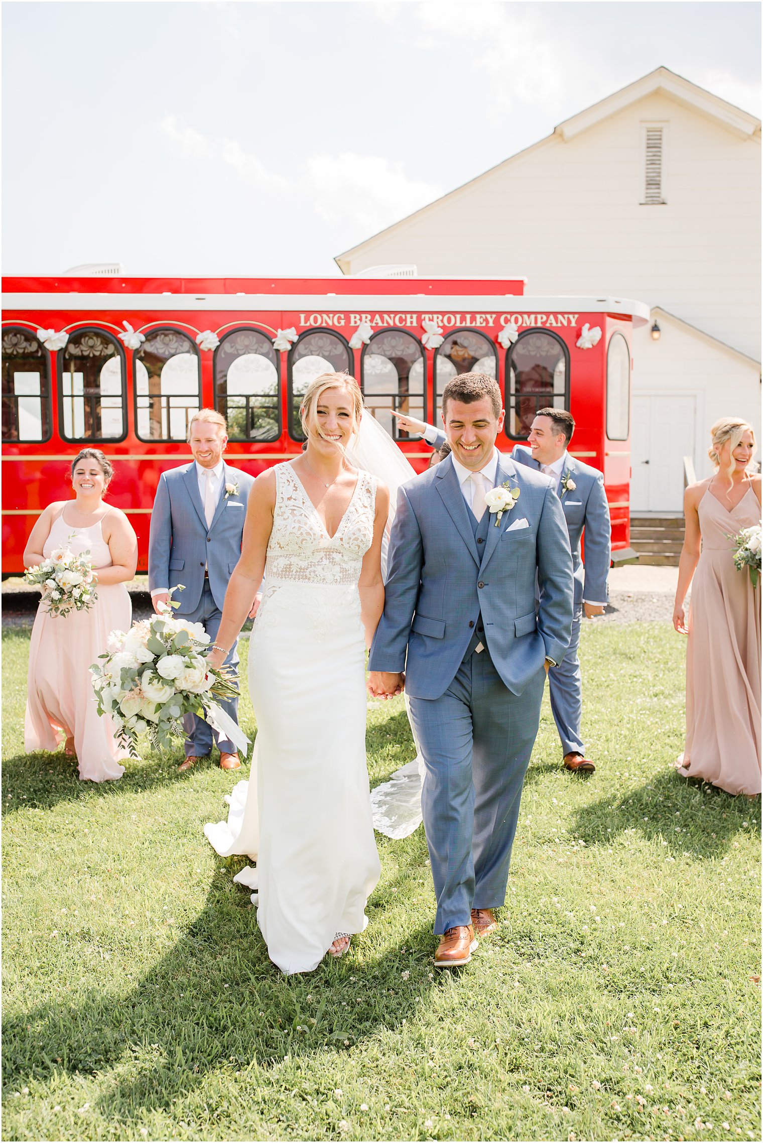 Candid photo of bride and groom walking in front of bridal party and red trolley 
