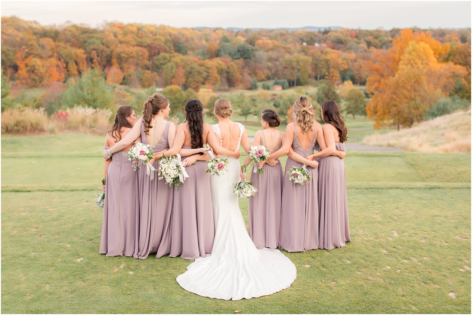 Bridesmaids hugging admiring view of fall foliage