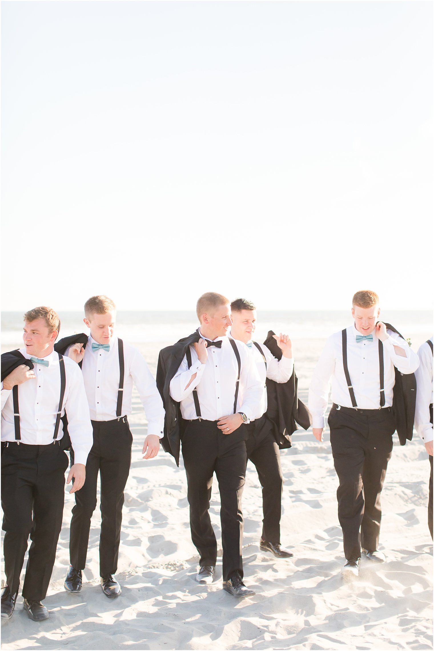 Groom walking on the beach with groomsmen