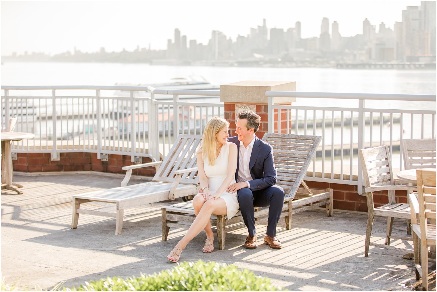 Couple sitting on wooden chair during Hoboken Rooftop Engagement by Idalia Photography