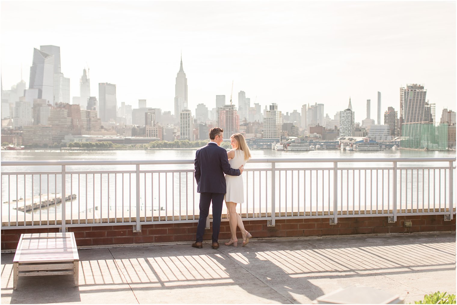 Engaged couple looking off at NYC | Hoboken Rooftop Engagement by Idalia Photography