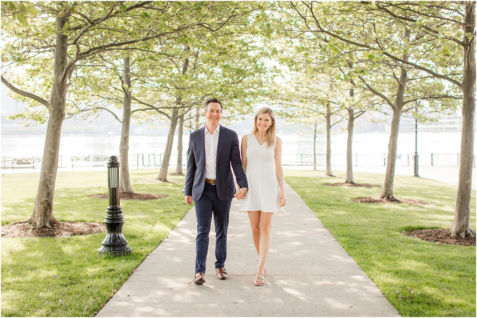 Bride and groom walking under tree canopy | Hoboken Rooftop Engagement by Idalia Photography