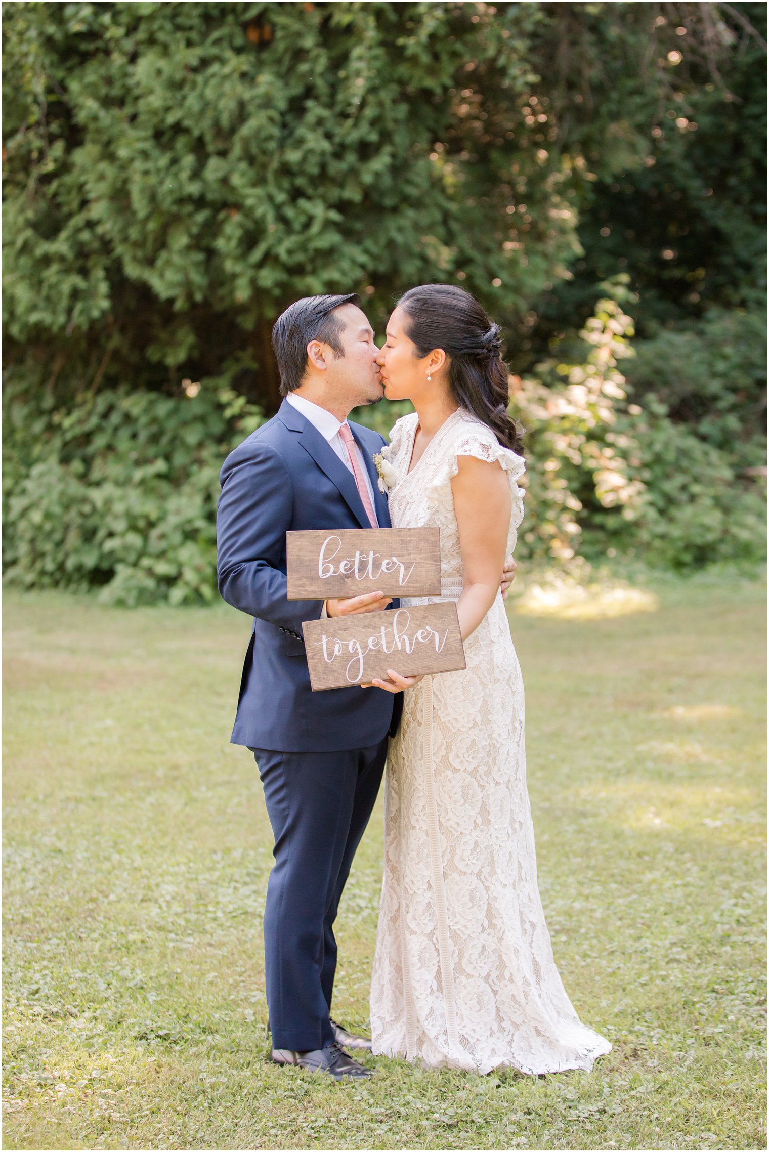 Bride and groom kissing and holding "Better Together" sign | NJ Intimate Wedding with a Gorgeous Arch by Idalia Photography