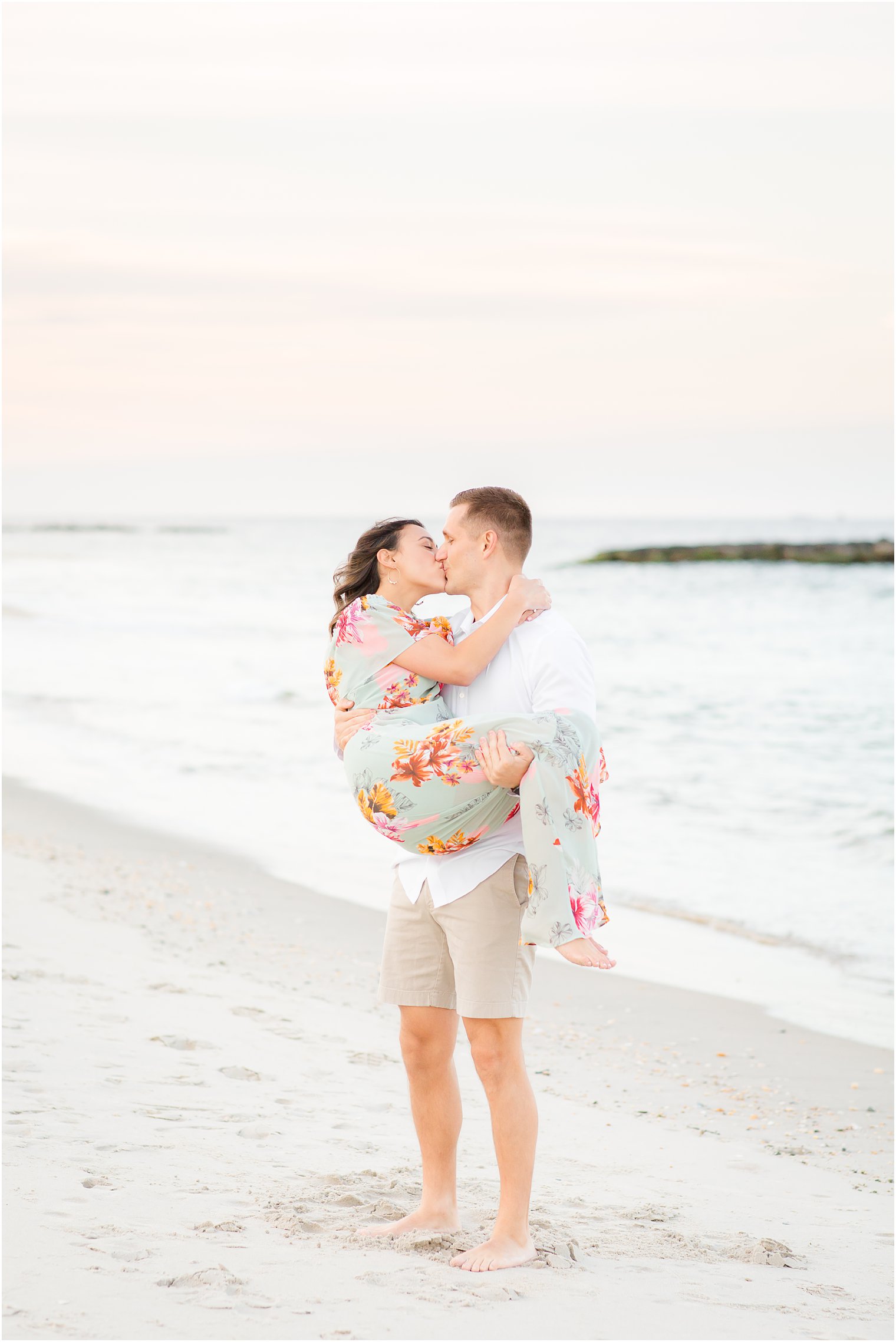 Groom lifting bride during beach engagement session 