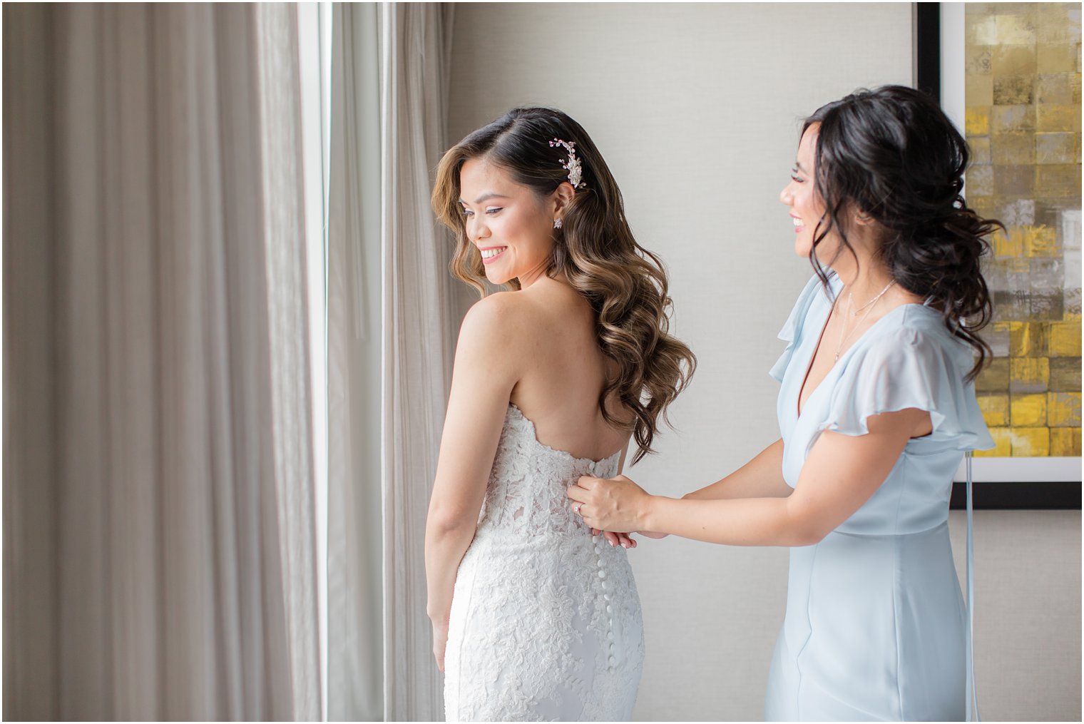 Maid of honor helping bride get dressed