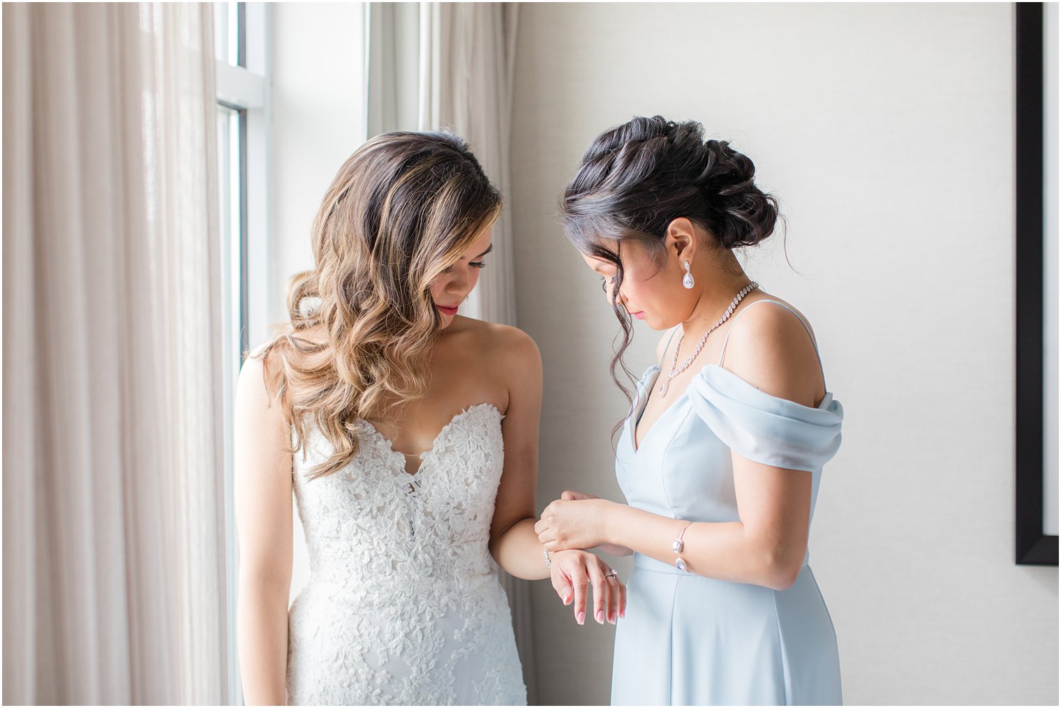 Maid of honor putting bracelet on bride