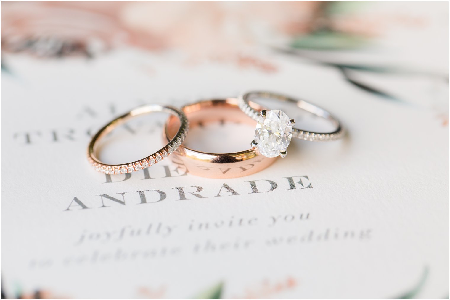 Wedding bands on top of floral invitation 