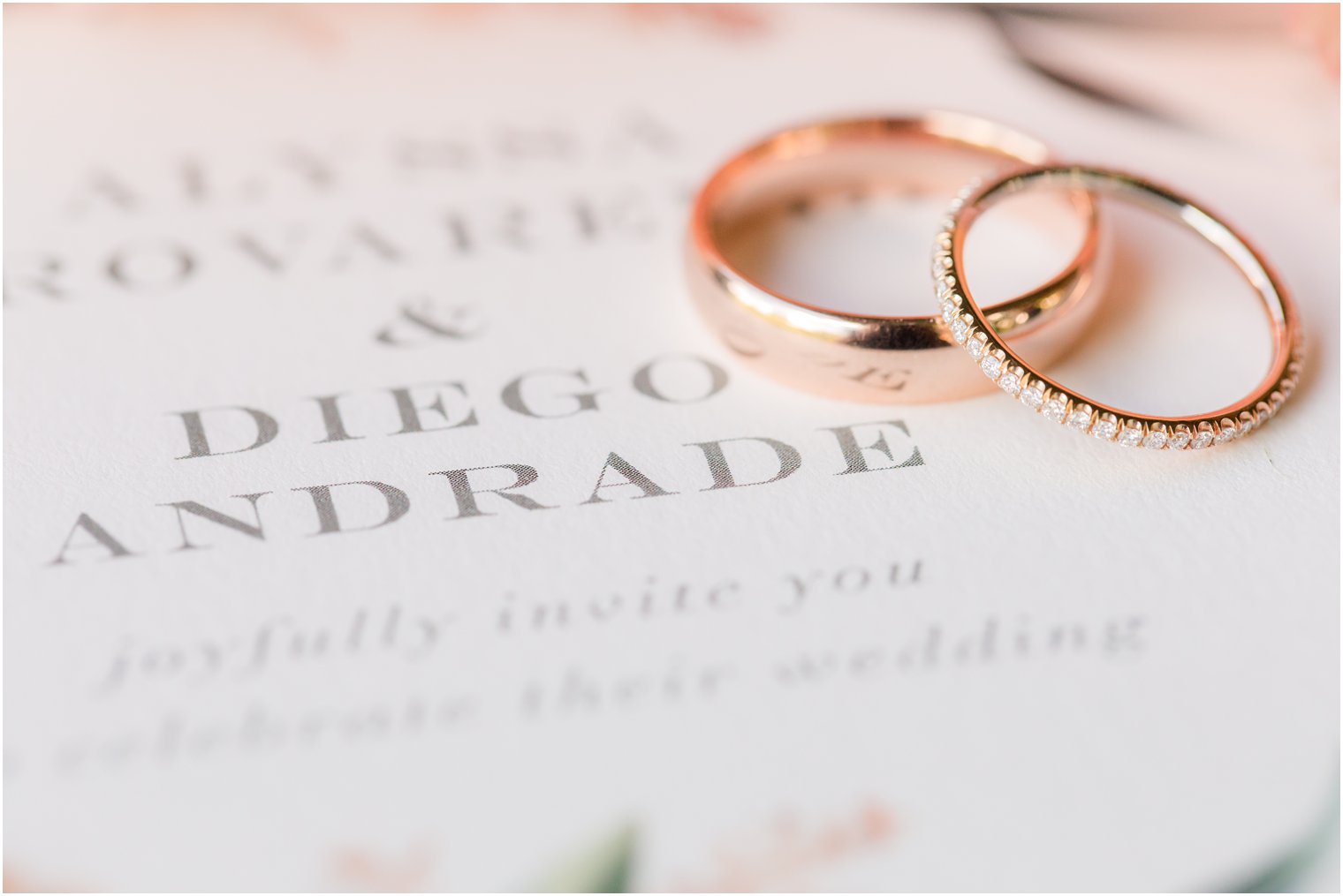 Rose gold wedding bands on floral invitation 