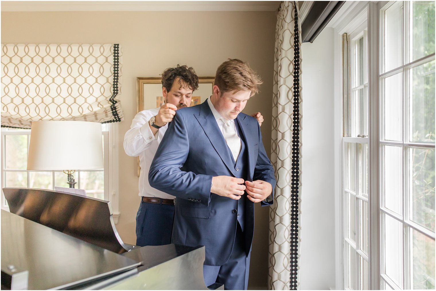 best man helping groom get dressed