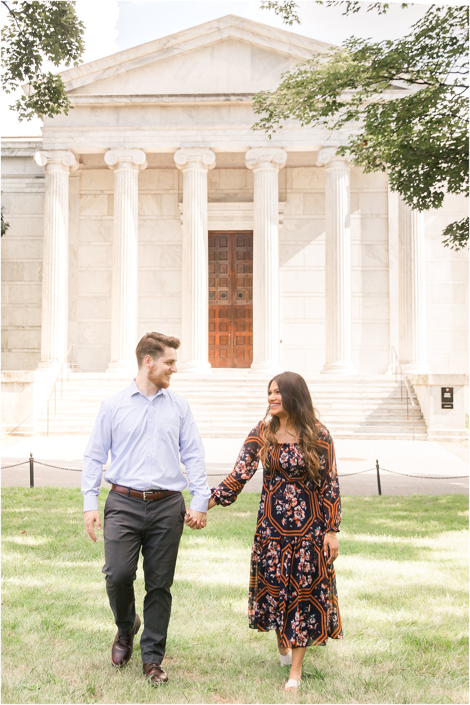 Engaged couple walking on the lawn in front of Clio Hall